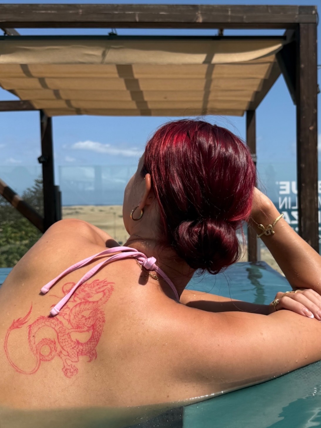 Red ink dragon tattoo across the shoulder blade
