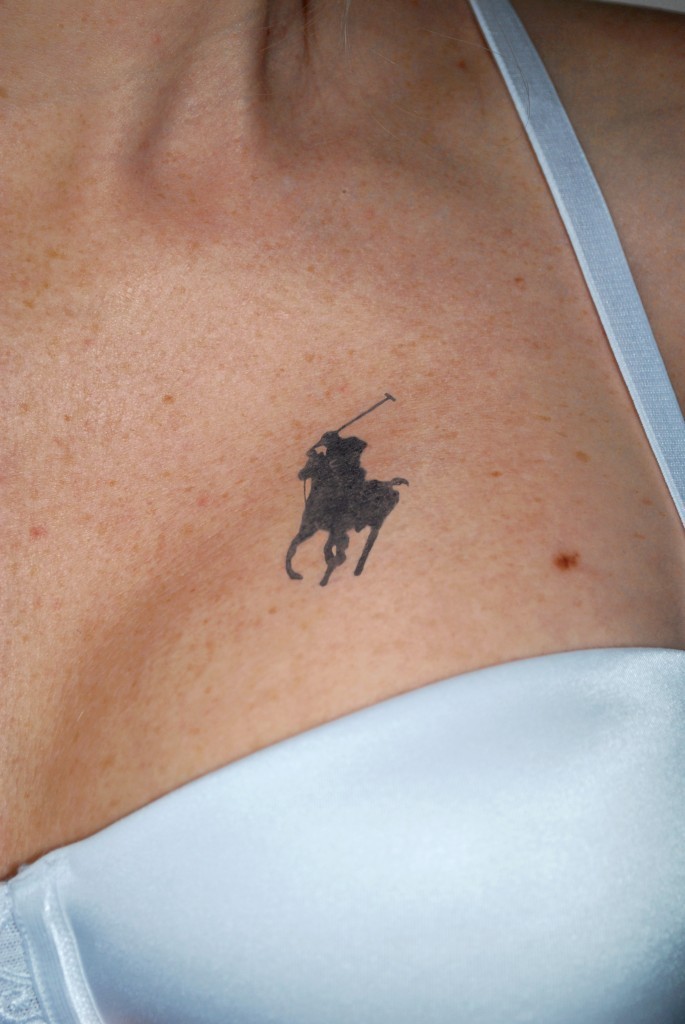 Close-up of a polo player silhouette tattoo on the collarbone above a white bikini top
