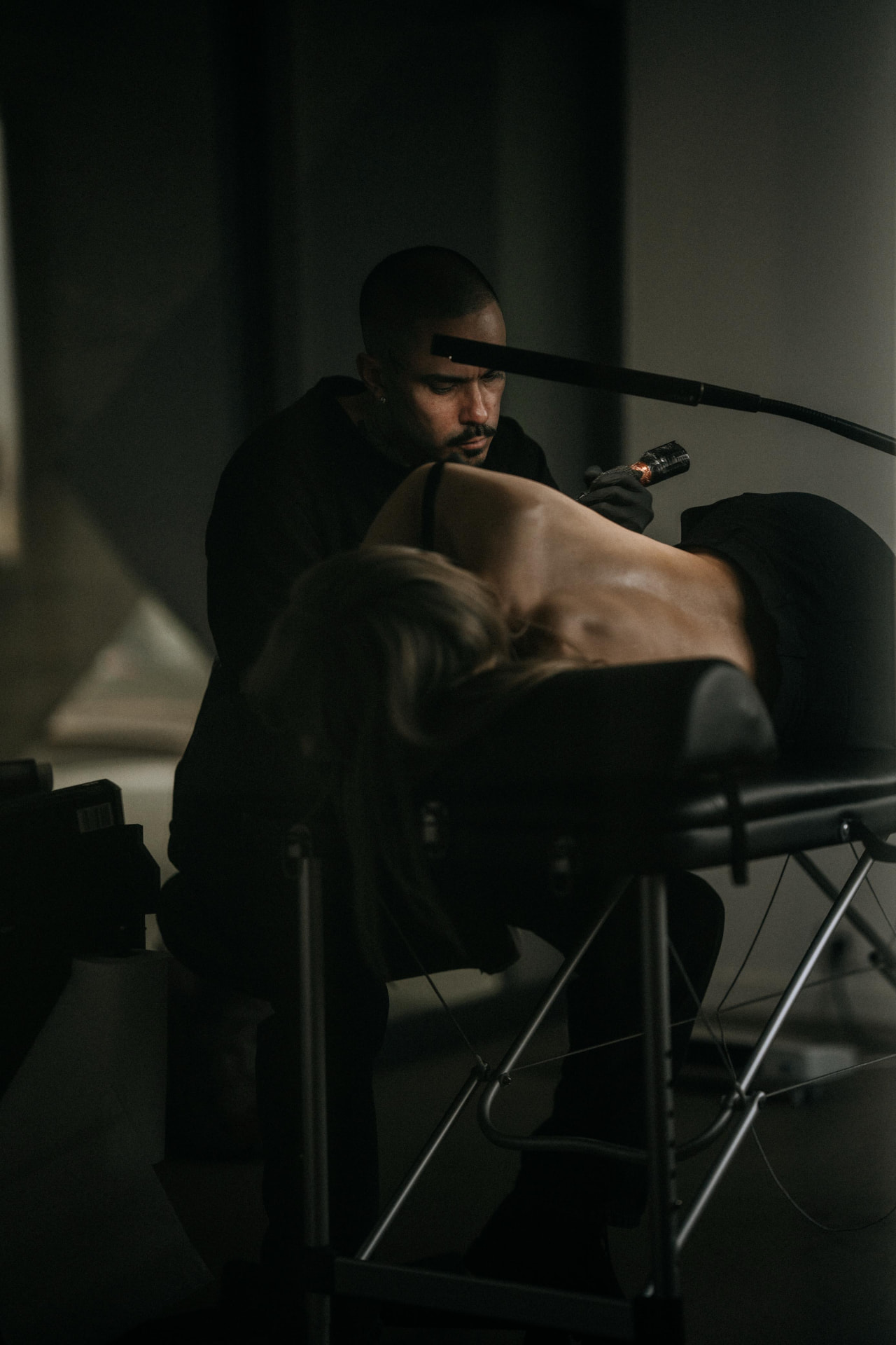 66onions tattooing a back piece in a dimly lit studio