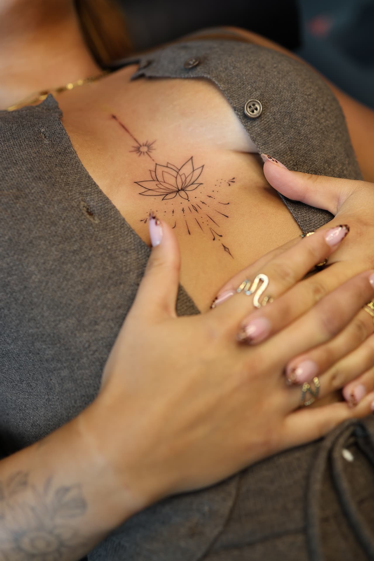 Fine line lotus and ornamental sternum tattoo
