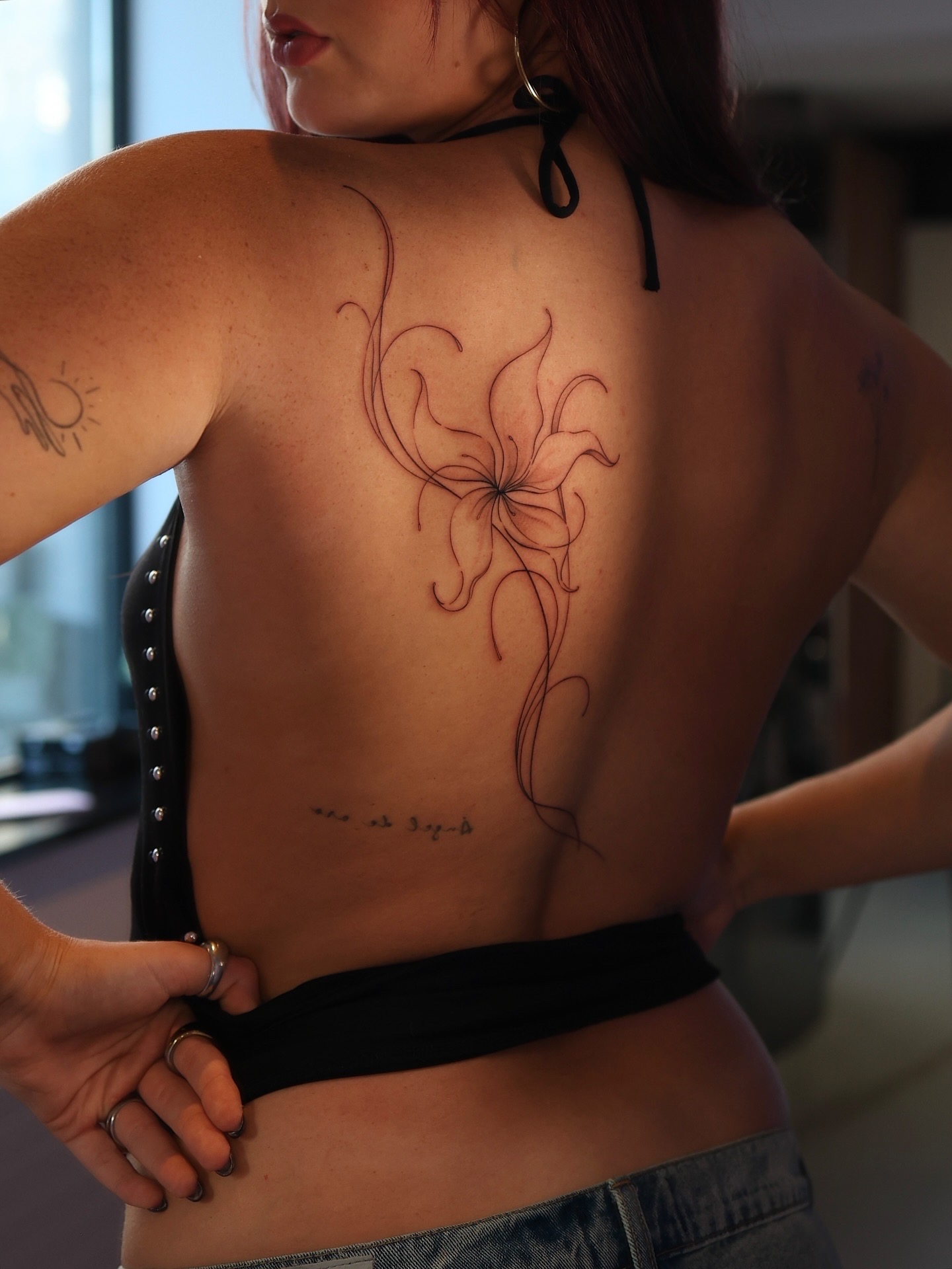 Large fine line floral tattoo flowing along the spine