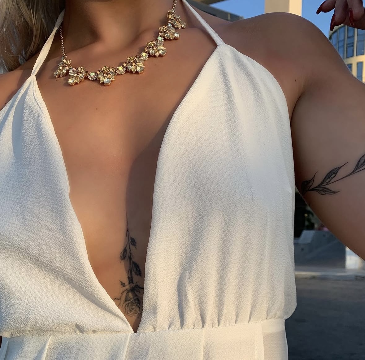 Fine line rose tattoo along the sternum in a white dress
