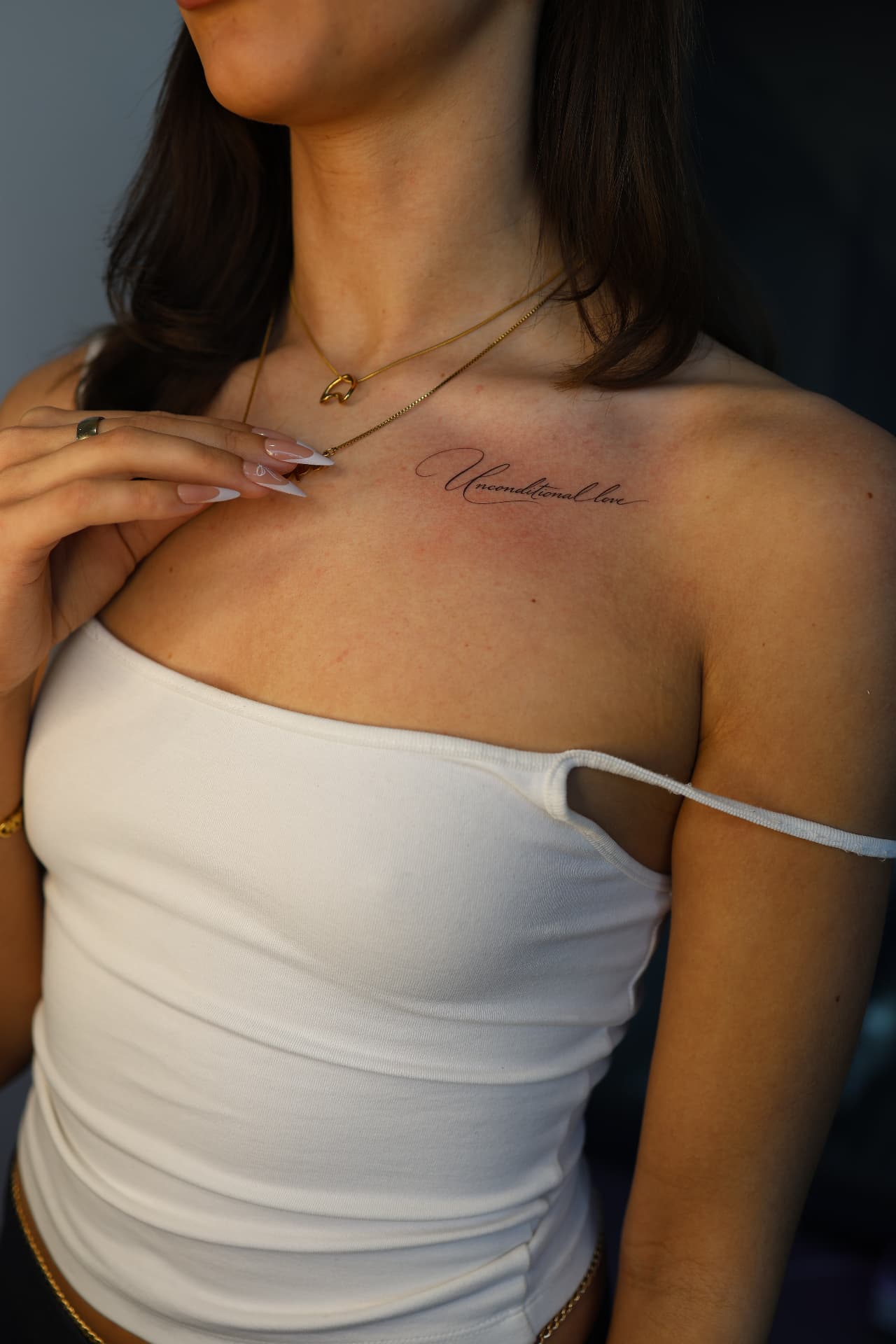 Calligraphy 'Unconditional love' tattoo across the collarbone