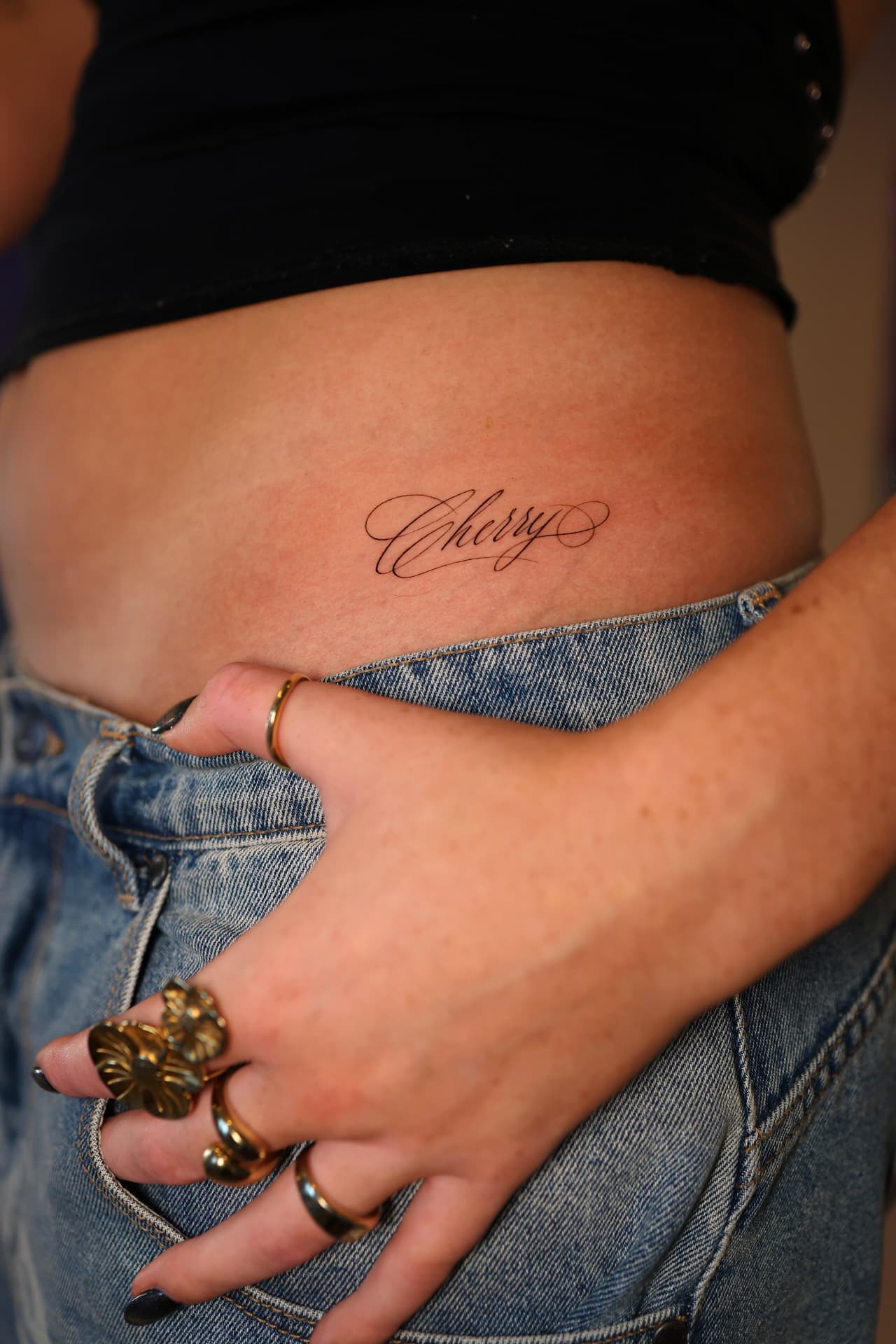 Calligraphy script tattoo on the hip above denim