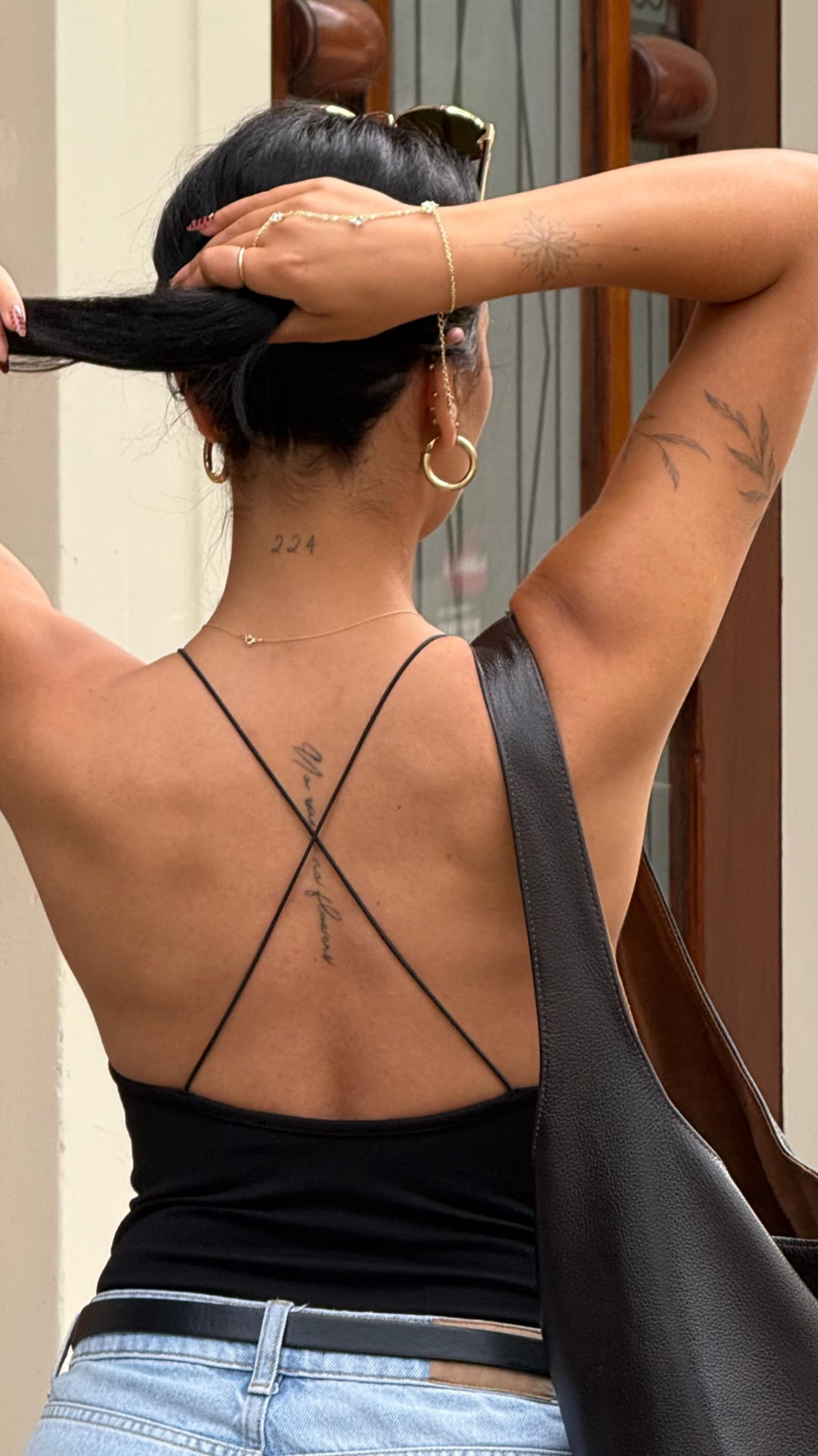 Fine line script spine tattoo with botanical arm pieces